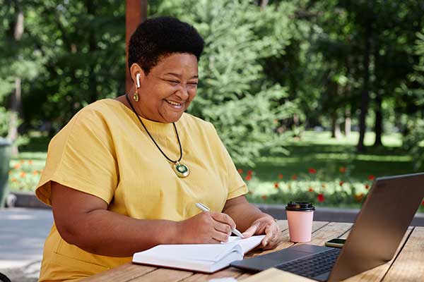 A woman sits outside and schedules a consultation on her laptop