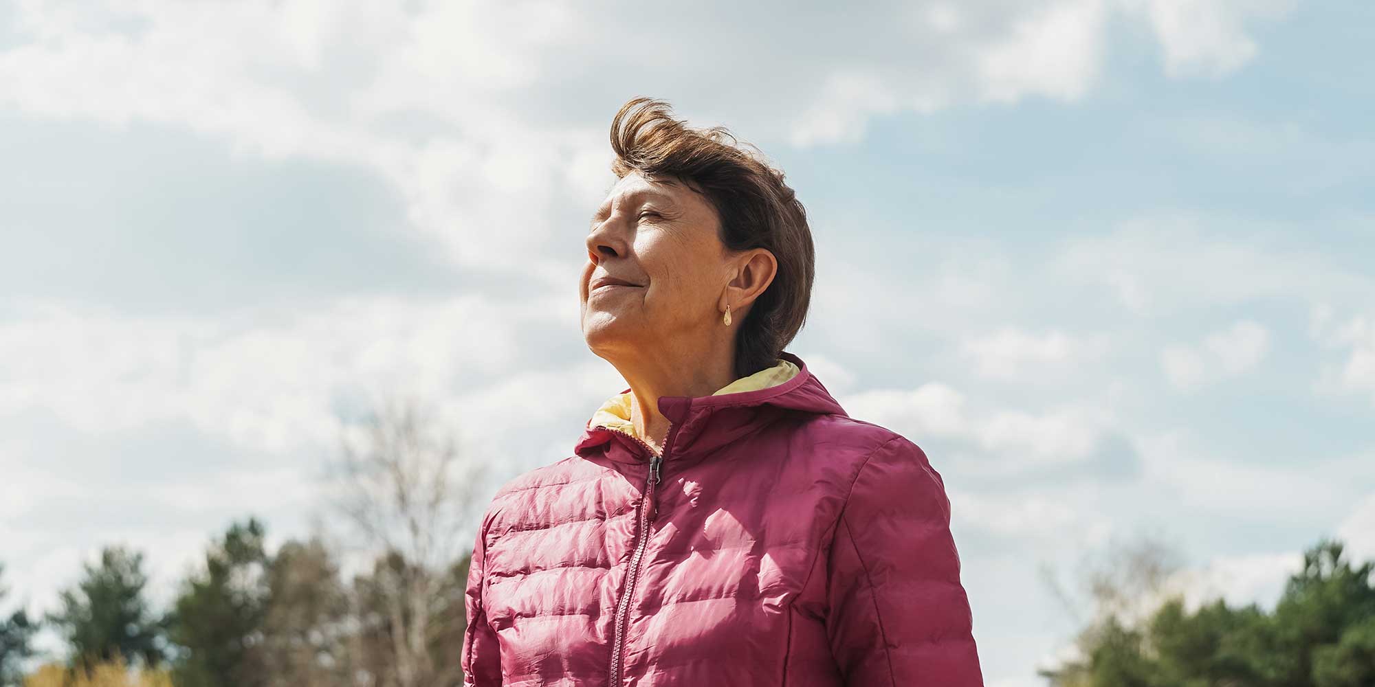 A senior woman stands outside breathing freely in the chilly air