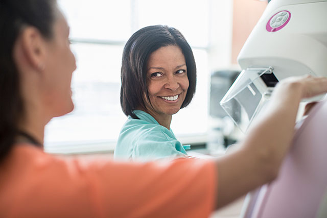 A nurse prepares a female patient for a mammogram