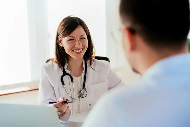 A patient speaks with a smiling doctor who is advising him on health insurance options