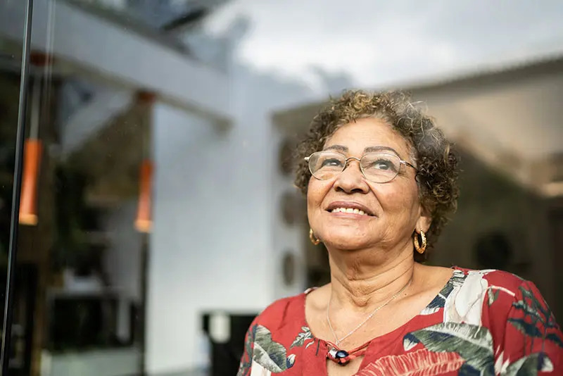 A senior woman gazes out the window smiling